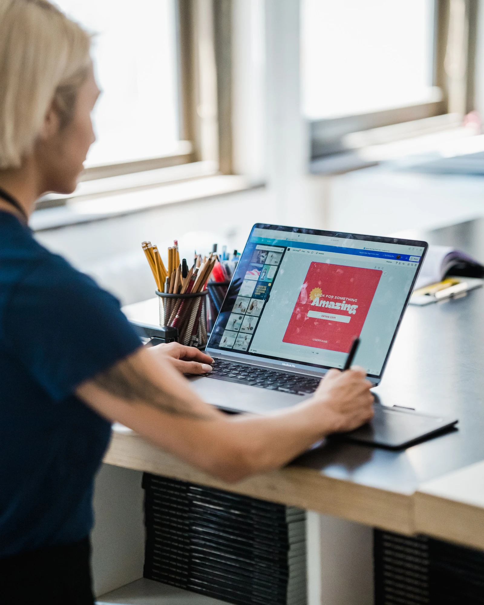Eine Designerin arbeitet am Laptop und Grafiktablett an einem visuellen Inhalt.